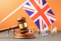 Wooden judge gavel, flag and plastic toys on a colored background, the concept of trials in the British Society