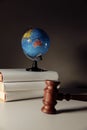 Wooden judge gavel and globe on books. International environment law concept. Vertical image Royalty Free Stock Photo