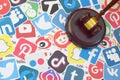 Wooden judge gavel lies on many paper logos of popular social networks and internet resources. Entertainment lawsuit concept