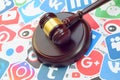 Wooden judge gavel lies on many paper logos of popular social networks and internet resources. Entertainment lawsuit concept