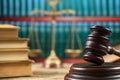 Wooden judge`s gavel. In the background, the weight of justice and law books. Royalty Free Stock Photo