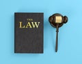 Wooden judge`s gavel and law book on blue background Royalty Free Stock Photo