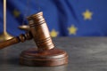 Wooden judge`s gavel and Scales of justice on grey table against European Union flag, closeup. Space for text Royalty Free Stock Photo