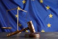Wooden judge`s gavel and Scales of justice on grey table against European Union flag Royalty Free Stock Photo