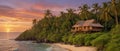 A wooden jungle house with a beautiful ocean view, with the sun setting into the horizon of the ocean