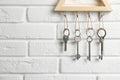 Wooden key holder on white brick wall indoors. Space for text Royalty Free Stock Photo