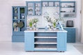 Wooden kitchen in easter decor. Cozy home decor. Blue kitchen interior with furniture. Stylish cuisine with flowers in vase.