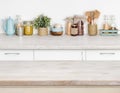 Wooden kitchen table over blurred furniture shelf with food ingredients Royalty Free Stock Photo