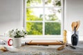 Wooden kitchen tabletop with white kitchenware and window with blurred plants and window  background. Royalty Free Stock Photo