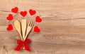 Wooden kitchen utensils with red bow paper red hearts on wooden background and empty space for text. Cooking spoon spatula and