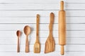 Wooden kitchen utensils on white wooden background with copy space. Spatula, spoons and rolling pin in row, top view Royalty Free Stock Photo