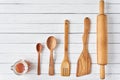 Wooden kitchen utensils on a white wooden background with copy space. Spatula, spoons and rolling pin in row, top view Royalty Free Stock Photo