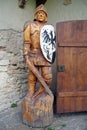 Wooden knight with sword and shield stands near entrance to castle