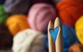 Wooden knitting needles on background of colorful merino wool ba