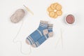 Wooden knitting needles, bamboo hook, ball of grey yarn, blue-grey socks from wool, cup of tea and cookies. Royalty Free Stock Photo