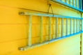 Wooden ladder hanging on yellow house wall Royalty Free Stock Photo