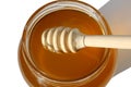 A wooden ladle lies in honey in a jar.