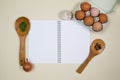 Wooden ladles with spices, eggs and garlic with a blank notebook page Royalty Free Stock Photo