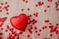 On wooden laminate floor lies red foil heart shaped balloon among white rose petals. Greeting card Royalty Free Stock Photo