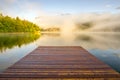 Wooden landing jetty at sunrise. Foggy morning at lake Bohinjsko, Slovenia.