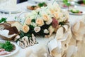 Wooden lettering lies behind a bouquet of beig roses on the dinner table Royalty Free Stock Photo