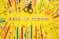 Wooden letters arranged in phrase back to school and office supplies on yellow background Royalty Free Stock Photo