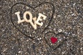 Wooden letters forming the word love with a red heart on a background of beach sand, inside a heart made with the fingers. concept Royalty Free Stock Photo