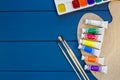 Wooden letters and notepads, pencils, watercolors, paintbrushes on classic blue background. Education, back to school concept.