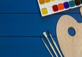 Wooden letters and notepads, pencils, watercolors, paintbrushes on classic blue background. Education, back to school concept.