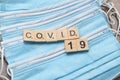 Wooden letters and numbers add up to the word: covid 19. Items are laid out on a protective mask Royalty Free Stock Photo