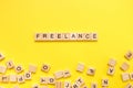 Wooden letters with the word freelance on a yellow background. Top view