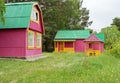 Wooden little cottages for tourists stand in the parkland in a blooming meadow among the trees on a summer day