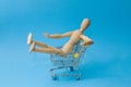 Shopping cart with wooden mannequin isolated on color background Royalty Free Stock Photo