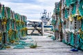 Wooden lobster traps stacked in rows on an old dock overlooking a harbour with fishing boats in Whiteway