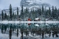 Wooden lodge in pine forest with heavy snow reflection on Lake O'hara at Yoho national park Royalty Free Stock Photo