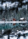 Wooden lodge in pine forest with heavy snow reflection on Lake O'hara at Yoho national park Royalty Free Stock Photo