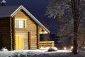 Wooden log cabin at winter night. Country house in winter evening can be used as postcard, wallpaper or poster Royalty Free Stock Photo