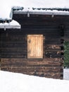 Wooden log house detail with closed shutter window during winter, deep snow Royalty Free Stock Photo