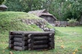 A wooden log house with a fragment of a wooden well in front and a basement overgrown with green grass Royalty Free Stock Photo