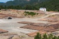 Wooden logs of pine woods in the forest and a distant white house. Logging in Pindus mountains Royalty Free Stock Photo