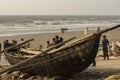 A wooden lonely fishing boat with few tourists on Digha sea beach. Selective focus