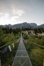 Wooden long footbridge above the deep gorge with a river beach at the bottom, between the rocks. Wild mountains in Swiss Alps