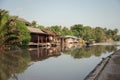 Wooden longtail boat sailing and traditional homestay floating on river at Amphawa
