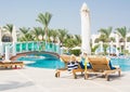 Wooden lounge chairs with striped bag near the pool at the resort