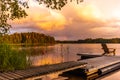 Wooden lounge chairs at Sunset on a pier on the shores of the calm Saimaa lake in Finland under a nordic sky with a rainbow Royalty Free Stock Photo