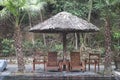Wooden loungers and chairs under a straw umbrella