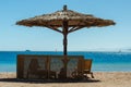 Wooden loungers under a bamboo beach umbrella on the beach against the sea and blue sky in Egypt Dahab South Sinai Royalty Free Stock Photo