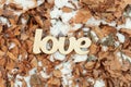 Wooden love sign outdoor on the ground with yellow leaves and snow Royalty Free Stock Photo