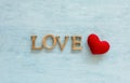 Wooden love text and red heart over blue background