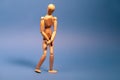Wooden man with bladder control problem on blue background Royalty Free Stock Photo